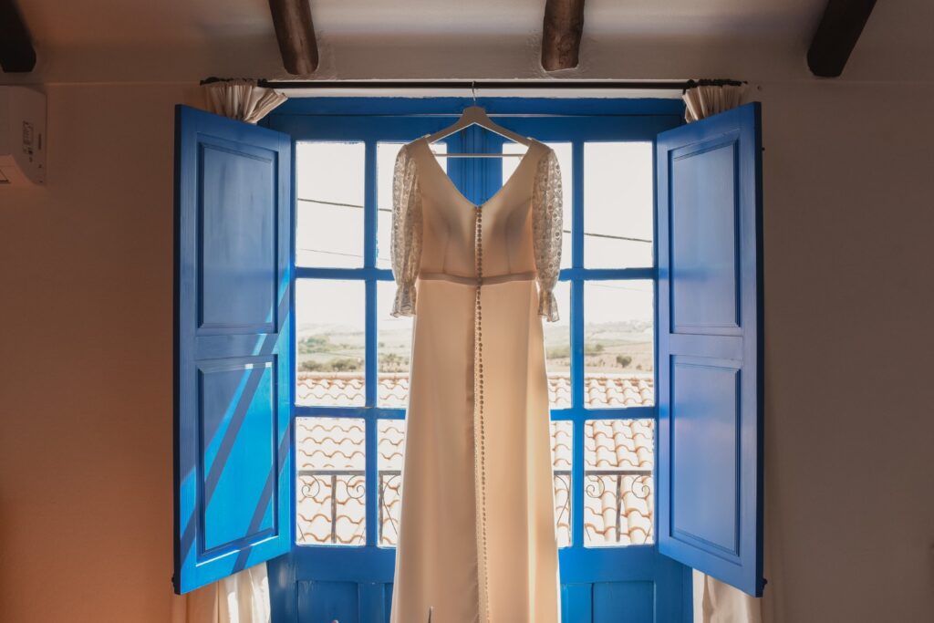 Fotografia de Casamento. Vestido da noiva pendurado à janela.