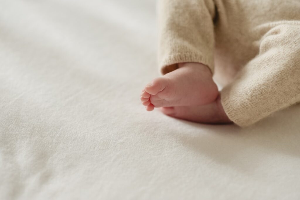Sessões fotográficas recém-nascido. Recém-nascido dorme. Pormenor de pés entrelaçados.