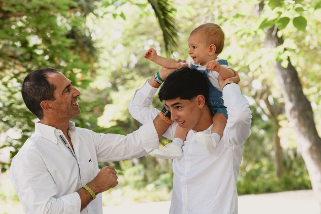 Sessões fotográficas de família. Sessões fotográficas em exterior, num jardim. Pai com os dois filhos rapazes.