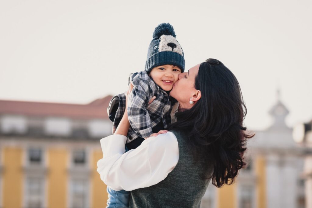 Sessões fotográficas de família. Sessões fotográficas em exterior, em Lisboa. Mãe que pega o filho ao colo e lhe dá um beijo no rosto.