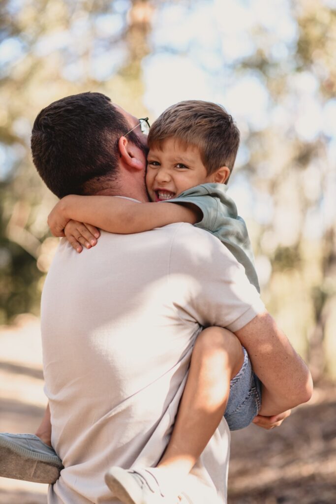 Sessões fotográficas de família. Sessões fotográficas em exterior, na natureza. 
Pai abraça filho.